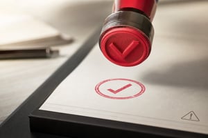 Illustration of a red rubber stamp approving a document while a small warning sign goes unnoticed, representing the approval process failure behind the Starbucks Korea controversy.