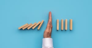 hand stopping a domino effect
