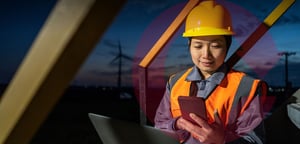 energy industry worker with helmet looking at phone