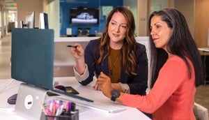 two women discussing work looking at a computer screen